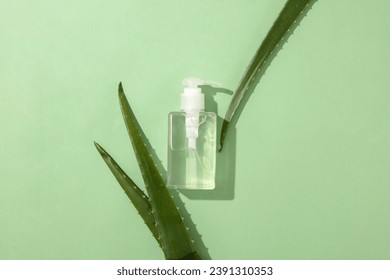 A bottle of hand sanitizer is placed in the center of the frame with fresh aloe vera leaves. Aloe vera gel is an ideal ingredient to replace the moisturizing and softening role of glycerin.