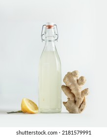 Bottle With Homemade Ginger Ale, Lemon And Gingerroot At White Background.  Front View. 