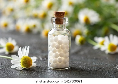 A Bottle Of Homeopathic Remedies With Fresh Chamomile Flowers