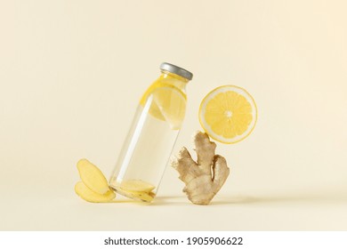 Bottle of infused water with ginger and lemon over light yellow background. Balanced still life of detox water and ingredients.