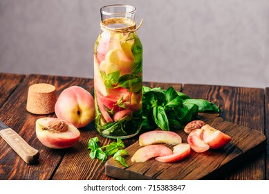 Bottle of Infused Water with Sliced Peach and Basil Leaves. Knife and Ingredients on Cutting Board. - Powered by Shutterstock