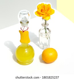 A Bottle Of Italian Limoncello, Lemon And Yellow Rose. Modern Minimalistic Still Life On A Geometric Background With Sunlight And Shadows. Square Shot.