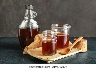 Bottle and jars of tasty maple syrup on dark background - Shutterstock ID 2193792179