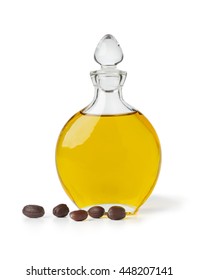 Bottle of Jojoba oil and seeds on white background