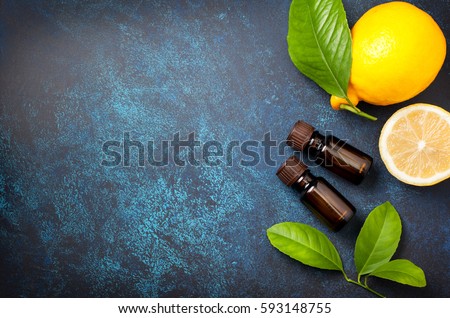 bottle with lemon essential oil, fresh lemon on a blue background