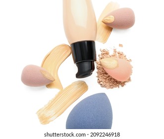 Bottle of makeup foundation, sponges and samples on white background, closeup