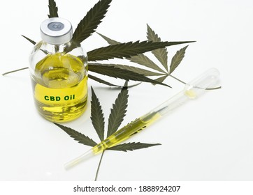 A Bottle With Medical Marijuana Oil With The Inscription Cbs Oil On A White Background With Some Dried Marijuana Leaves