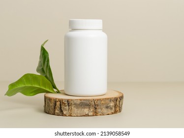 Bottle for medical pills or vitamins on wooden stand with green leaves, organic herbal vitamins, template bottle - Shutterstock ID 2139058549