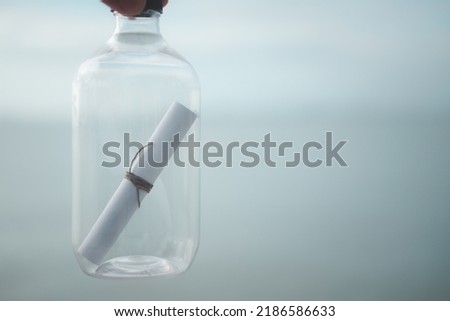 Bottle with message inside on sea and sky background, close-up