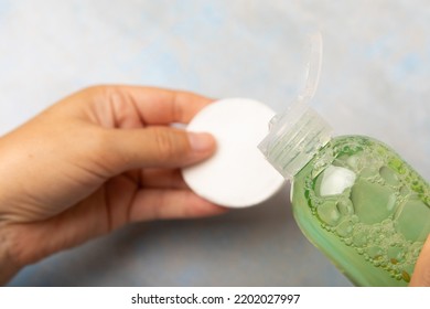 Bottle With Micellar Water And Cotton Pad In Hands. Apply Tonic On A Cotton Pad. Cleanse The Skin From Sebum And Makeup. Composition On A Marble Background. Beauty Concept. Copy Space Text. Flat Lay