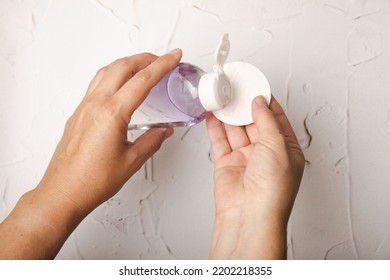 Bottle With Micellar Water And Cotton Pad In Hands. Apply Tonic On A Cotton Pad. Cleanse The Skin From Sebum And Makeup. Composition On A Marble Background. Beauty Concept. Copy Space Text. Flat Lay