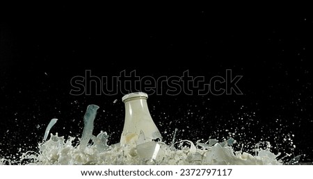 Bottle of Milk Exploding against Black Background