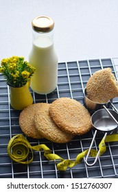 A Bottle Of Milk And Low Calories Sesame Biscuits With Measuring Tape: Healthy Lifestyle Concept (selective Focus Image)