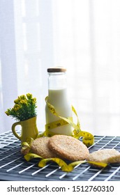 A Bottle Of Milk And Low Calories Sesame Biscuits With Measuring Tape: Healthy Lifestyle Concept (selective Focus Image)