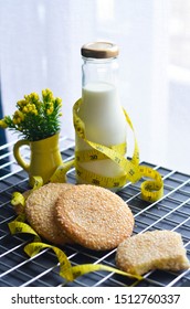 A Bottle Of Milk And Low Calories Sesame Biscuits With Measuring Tape: Healthy Lifestyle Concept (selective Focus Image)