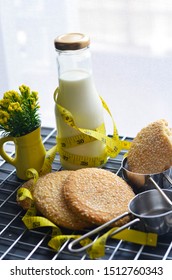 A Bottle Of Milk And Low Calories Sesame Biscuits With Measuring Tape: Healthy Lifestyle Concept (selective Focus Image)