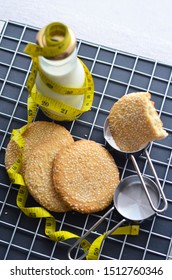 A Bottle Of Milk And Low Calories Sesame Biscuits With Measuring Tape: Healthy Lifestyle Concept (selective Focus Image)