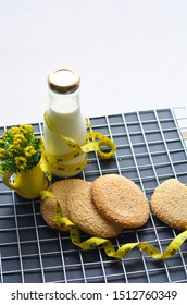 A Bottle Of Milk And Low Calories Sesame Biscuits With Measuring Tape: Healthy Lifestyle Concept (selective Focus Image)