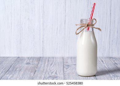 Bottle of milk with red straw, wooden background - Powered by Shutterstock