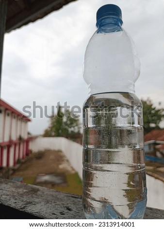 a bottle of mineral water by the window with the building behind it
