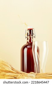 Bottle Of Natural Home Made Beer And Empty Glass With Bouquet Of Rye And Wheat On A Light Background With Copy Space. Concept Of Harvest And Oktoberfest. Vertical Format