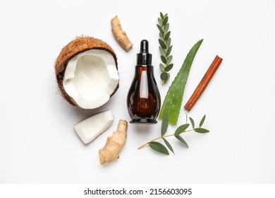 Bottle Of Natural Serum With Coconut, Ginger, Plant Leaves And Cinnamon On White Background