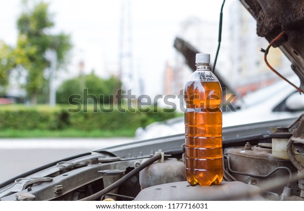 Bottle of new\
motor oil standing on open car\
hood.