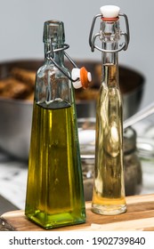 A bottle of olive oil and a bottle of vinegar on the table. One bottle is in focus and the other bottle is intentionally out of focus (blurred). - Shutterstock ID 1902739840