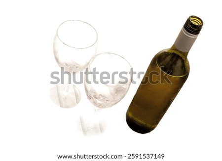 Bottle of opened white wine with two empty wine glasses viewed high angle on a wooden table conceptual of a celebration or entertaining