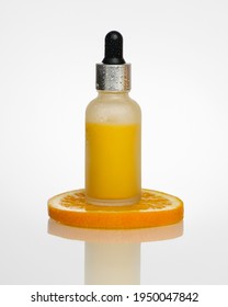 A Bottle Of Orange Serum Stands On An Orange Slice.