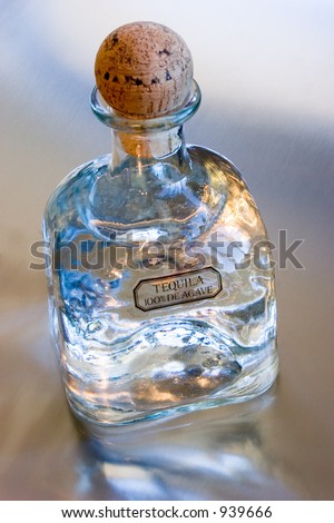 Bottle of Patron Silver Tequila on a reflective metal surface.