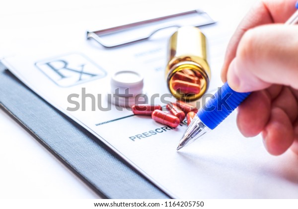 Bottle
with pills and doctor writing prescription
receipt