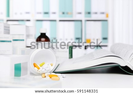 bottle pills and medicine capsule on desk with medical book, drugs and tablet boxes  in background
