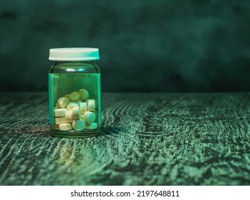 Bottle Of Pills On A Green, Medical, Grunge Background With Copy Space For Text. A Social Issues Concept