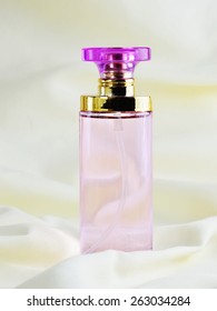 Bottle of pink perfume on soft fabric.
