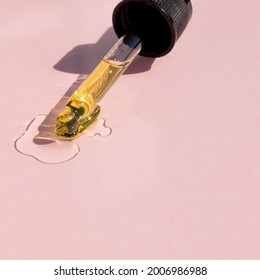 Bottle Pipette Dropper And Liquid Yellow-orange Retinol Or Vitamin C Gel Or Serum On A Pink Background.