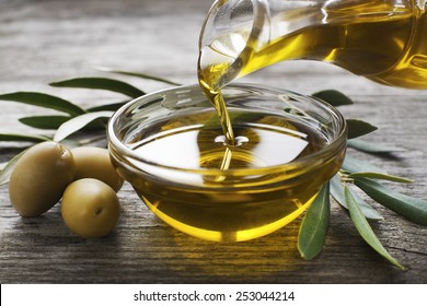 Botella vertiendo aceite de oliva virgen en un bol cerca
