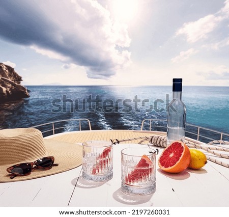 Bottle of pure water and two glasses and ripe grapefruit on deck of private yacht, cruise ship during summer vacation, outdoors. Health, fashion, style, love, travel, vivid impressions.