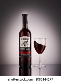 Bottle of red semi-sweet wine Chochori Alazani valley and glass of red wine on a grey background with reflection. Georgian wine collection. Produced in Georgia.