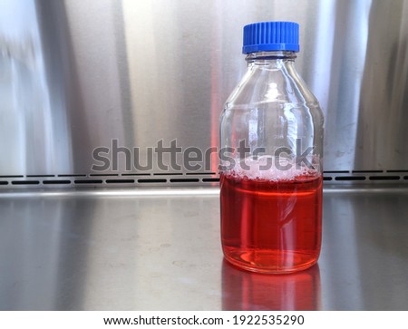 A bottle of red solution inside a steel cabinet                              