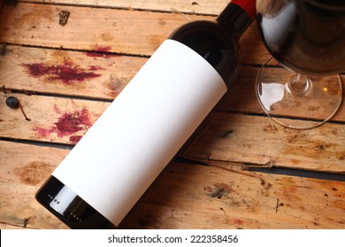 Bottle Of Red Wine With A Blank Label And A Full Glass In A Used Wooden Crate With Grape Juice Marks