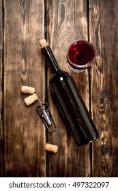 Bottle Of Red Wine With A Corkscrew And Corks. On A Wooden Table.