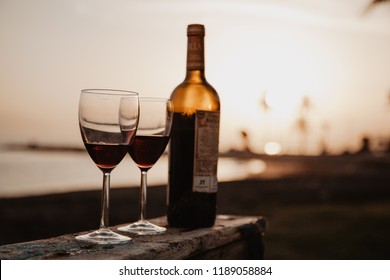 Bottle with red wine and glasses on the wooden, behind sunset - Powered by Shutterstock