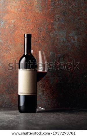 Bottle of red wine with old empty label on rusty brown background. Frontal view with space for your text.