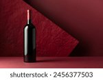 Bottle of red wine on a red background. Copy space for your text.