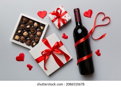 Bottle of red wine on colored background for Valentine Day with gift and chocolate. Heart shaped with gift box of chocolates top view with copy space. - Powered by Shutterstock