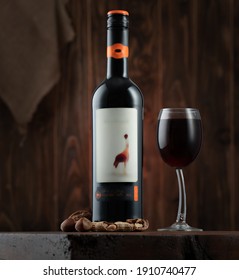 Bottle of red wine on dark wood background with a wine glass