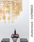 Bottle of red wine on a table, in a room decorated with beautiful chandelier. Focus on the table.
