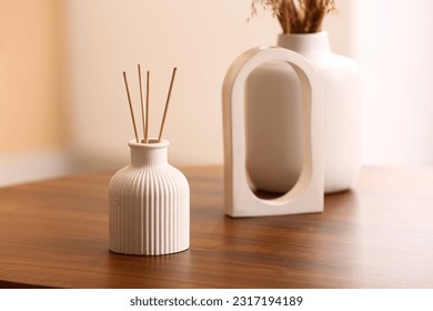 Bottle of reed diffuser and decor on table in room, closeup