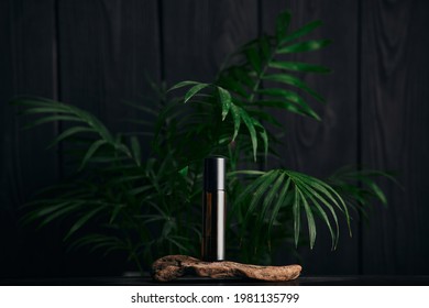 A Bottle Of Roller Perfume On Wood On A Black Background. Advertising Photo. Mockup